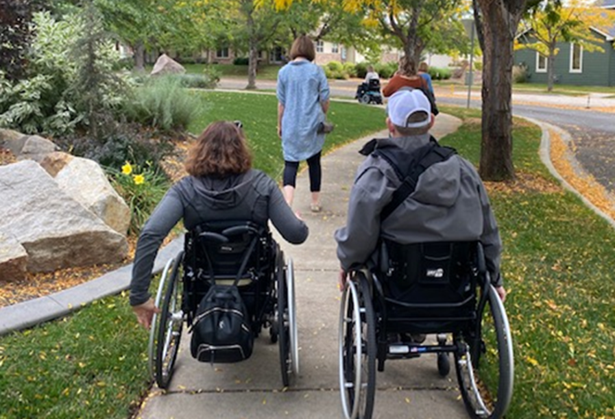 people in wheelchairs going down a path in the park.