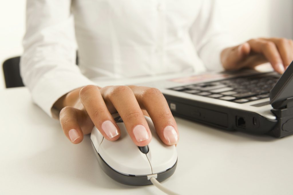 Womans hands touching computer mouse and keys of black opened laptop