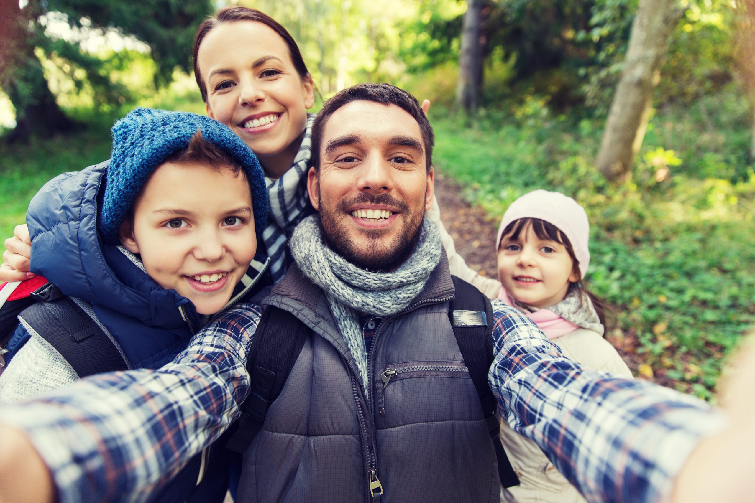 a family showing a dad, mom and two children in the forest.